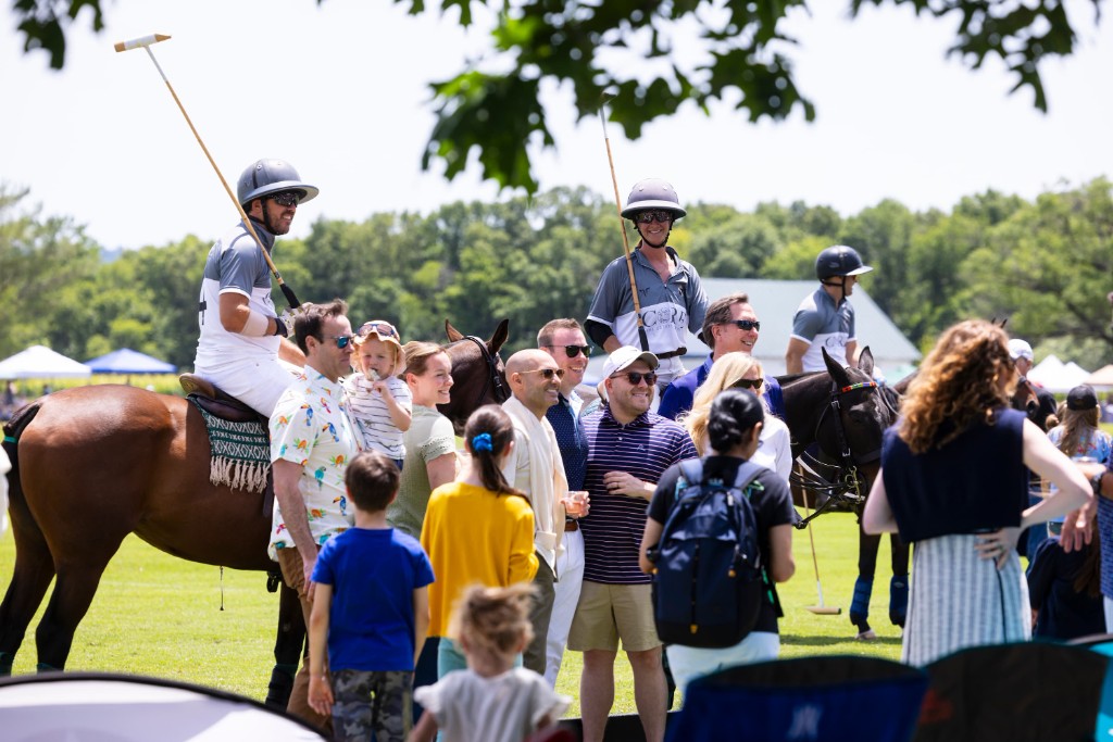 Spectators and polo players posing together on the field